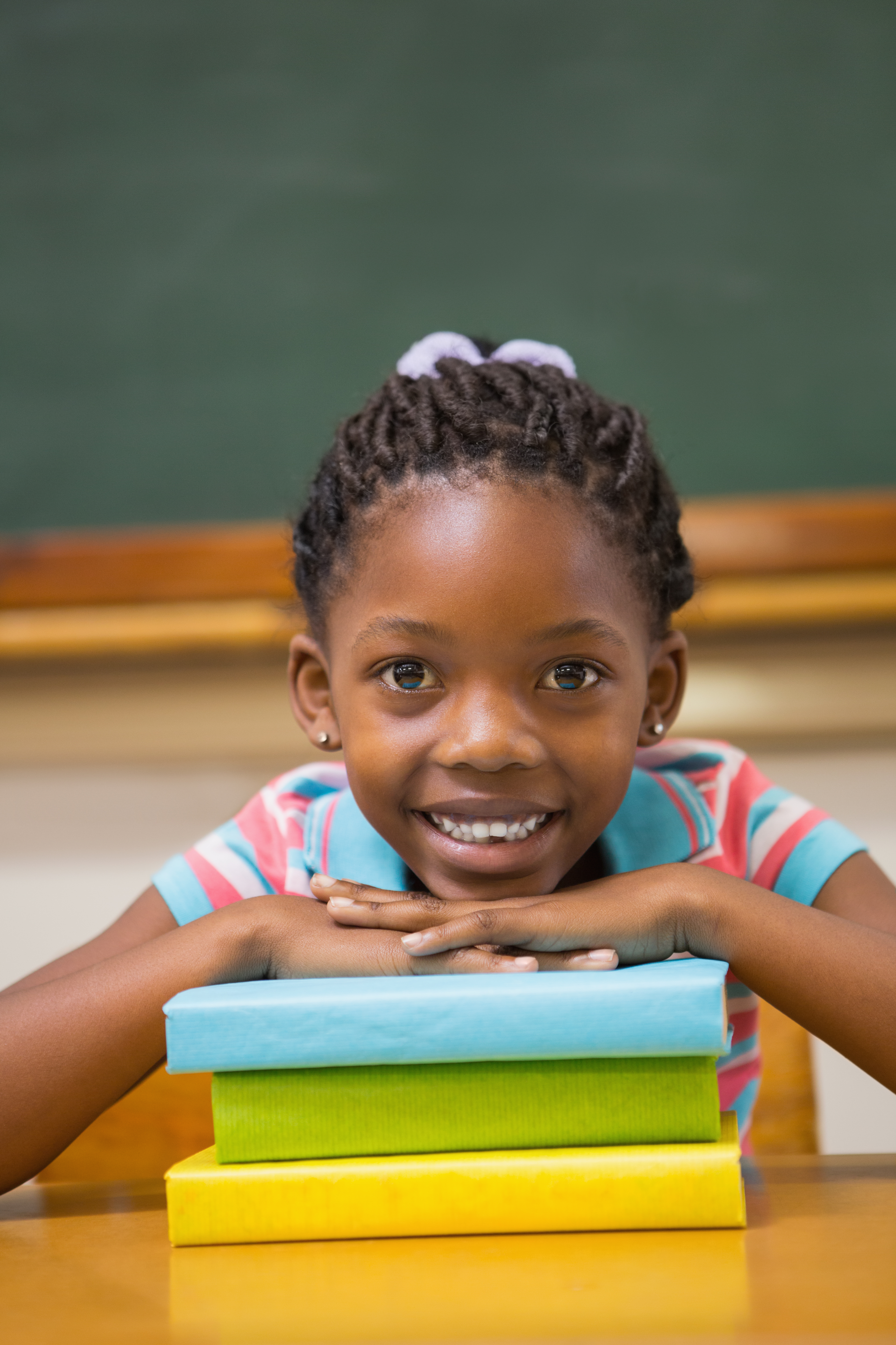 A smiling girl at her classroom desk with colourful markers